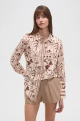 Camisa de manga larga con estampado de motivos playeros en tonos marrones sobre fondo beige, cuello camisero y cierre frontal con botones.