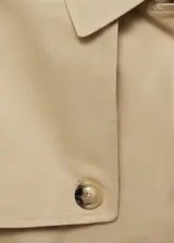 Trench coat negro con cuello de solapa, doble botonadura, trabillas en los puños, cinturón ajustable y abertura posterior en el bajo.