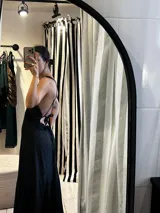 Vestido largo de silueta fluida confeccionado en seda con detalles de encaje. Presenta un diseño negro con estampado de lunares blancos, escote en V profundo y espalda descubierta con tiras cruzadas. La falda cuenta con paneles de encaje que aportan movimiento y delicadeza.