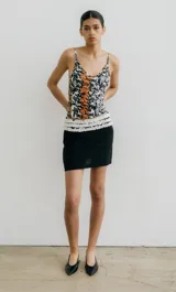 Minifalda negra de corte recto con detalle de volados blancos en la cintura.