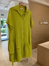 Vestido camisero color verde lima, de lino, fabricado en Italia, de manga corta, con botones de nácar y un volado en el ruedo final. Además, cuenta con un volado superior en un solo lado, creando un efecto irregular y con diseño.