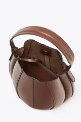 Bolso marrón formato saca con asa de mano y tira bandolera extraíble. Incluye cartera con bolsillo extraíble y cierre mediante botón imantado.