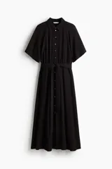 Vestido midi negro con cuello camisero, mangas cortas tipo raglán y botonadura frontal. Presenta elástico en la cintura y cinturón extraíble para atar.