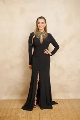 Vestido largo negro con cuello mao bordado con lentejuelas doradas, manga larga y tajo lateral con detalle de encaje.