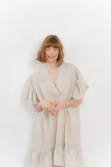 Vestido corto color beige confeccionado en algodón, con escote en V con detalles bordados, mangas cortas amplias con volados y falda con ruedo en volado.