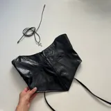 Top negro de cuero sintético con textura de cocodrilo, cierre frontal con cremallera y tirantes finos.