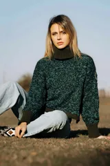 Sweater tejido a mano con dos agujas, 100% lana, de color verde oscuro con detalles en azul. Tiene cuello alto y silueta recta.