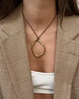 Collar con dije circular irregular de alpaca y plata 925, con hilo de algodón natural.