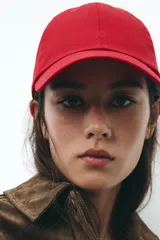 Gorra roja con visera confeccionada en hilatura de algodón 100% y ajuste en la parte posterior.