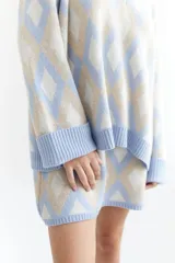 Sweater de lana color beige con diseño geométrico de rombos en tonos beige y blanco, cuello en V y corte holgado.