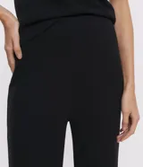 Pantalón negro de punto, modelo wide leg, con cintura elástica y superficie lisa.