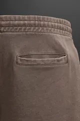 Bermuda jogger negra confeccionada en tejido de algodón con interior de rizo, cintura elástica ajustable con cordón y bolsillos laterales.