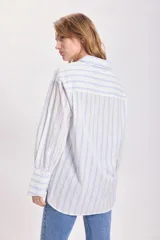 Camisa blanca con rayas verticales celestes, de corte clásico y manga larga.