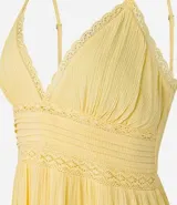 Vestido corto negro de viscosa certificada, con escote en V ribeteado con encaje, breteles finos y cuerpo con frunces horizontales. La falda tiene un volante con detalle de encaje en el ruedo.