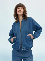 Campera bomber de denim azul con cierre frontal, cuello mao y bolsillos laterales.