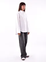 Camisa blanca a rayas verticales color ladrillo, de corte recto y mangas largas con puños abotonados.
