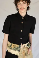 Camisa negra de manga corta con botones nacarados y corte estampado en el delantero.