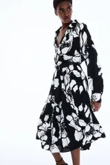 Vestido camisero midi de viscosa con estampado floral en blanco y negro, cuello camisero, tapeta de botones oculta, mangas raglán largas con puños sencillos y costuras fruncidas en la pollera.