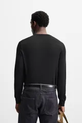 Jersey negro de lana con acabado mercerizado, corte relaxed fit, cuello redondo y manga larga con terminaciones en rib.