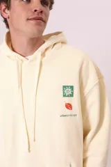 Sudadera con capucha de color verde oscuro (o verde petróleo) con efecto lavado, corte holgado y bolsillo canguro. Presenta un pequeño bordado blanco en el pecho con un diseño floral y texto.