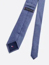 Corbata azul con pequeños lunares azul marino, confeccionada en seda texturizada.