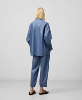 Sobrecamisa azul de cuero sintético con cuello mao, cierre frontal con botones, bolsillo de parche en el pecho, mangas largas y corte asimétrico.