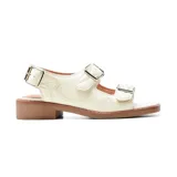 Sandalias bajas de cuero sintético color blanco hueso, con tres tiras horizontales con hebillas metálicas plateadas.