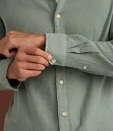 Camisa de hombre color verde menta, confeccionada en algodón texturizado con patrón melange. Presenta cuello inglés, manga larga y abotonado frontal. El corte es de estilo comfort, más generoso en sus medidas para mayor comodidad.