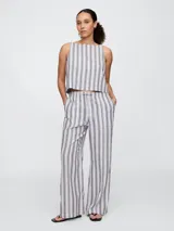 Pantalón largo de lino a rayas verticales blancas y azules, de corte palazzo con cintura alta y lazo ajustable.