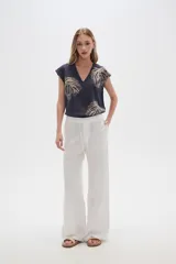 Pantalón blanco de rayon, corte ancho y tiro medio, con lazo ajustable en la cintura.