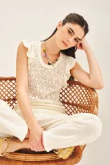 Musculosa color crema tejida en hilo de algodón con punto desagujado, calce al cuerpo y volados en las sisas.