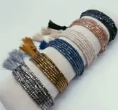 Set de pulseras elásticas con cuentas cuadradas de colores y borlas decorativas.