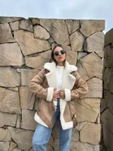 Campera gamulán color beige con interior de piel sintética blanca, cierre cruzado con cremallera y cinturón con hebilla.