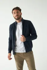 Campera negra de felpa con cierre frontal, bolsillos laterales, puños y logo bordado en el pecho.