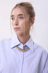 Camisa celeste de corte amplio, con cuello clásico y mangas largas abullonadas.