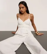 Mono blanco de pantalón ancho (pantalona) con escote cruzado en V y breteles finos ajustables.