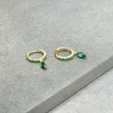 Aros dorados tipo argolla con incrustaciones de circonitas verdes y dije colgante de circonita verde en forma de lágrima.