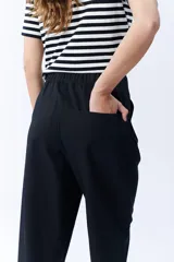Pantalón negro de corte ancho, con pinzas en la cintura y bolsillos laterales.