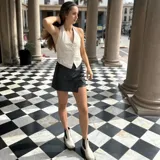 Chaleco crudo sin espalda, con cuello halter y cierre frontal con botones.