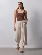 Pantalón capri plisado color beige, marca Dictionary, con pretina ancha elastizada y bolsillos delanteros.