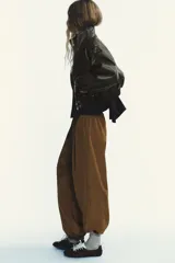 Pantalón de tiro medio color marrón claro, con cintura elástica, bolsillos laterales ocultos y puños elásticos.