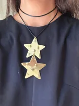 Gargantilla de cuero negro con dos dijes de estrella dorada texturizadas.