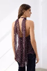 Top marrón con estampado de lunares blancos, cuello halter con lazo y detalle de logo dorado.