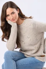 Buzo tejido de abrigo color beige, con cuello redondo, mangas largas y delicado diseño bordado en el frente con motivos florales en tonos pastel.