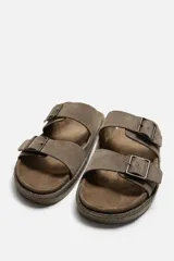 Sandalias marrones de piel con doble tira ancha en el empeine y cierre mediante hebilla. Plantilla con horma anatómica y suela forrada de yute.