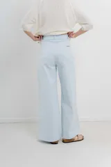 Pantalón de tiro alto, corte palazzo amplio y fluido, color celeste claro. Presenta bolsillos delanteros y traseros tipo jean, con logo metálico Peach en la parte posterior.