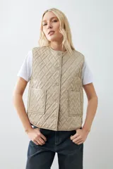 Chaleco capitoneado reversible a rayas azules y blancas con ribete color crema. Tiene cuello redondo, cierre con botones a presión y bolsillos de parche. El reverso es liso color tostado.