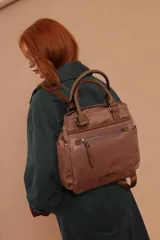 Mochila bandolera color marrón con herrajes color peltre. Tiene un compartimento principal amplio con cierre, un bolsillo frontal con cierre y dos bolsillos laterales abiertos. Incluye correa ajustable para usar al hombro o cruzada.