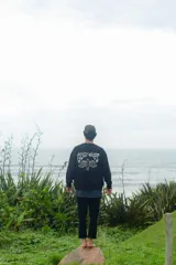 Buzo negro con estampado en la espalda que dice "Glossy Waves" con una tabla de surf.