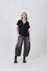 Blusa holgada de poliéster color blanco, con escote en V profundo y pinzas frontales que generan caída. Mangas cortas.